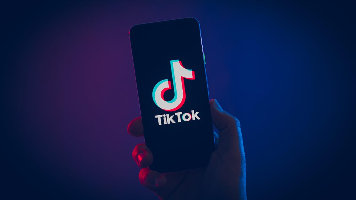 Hand holds up phone displaying TikTok logo 