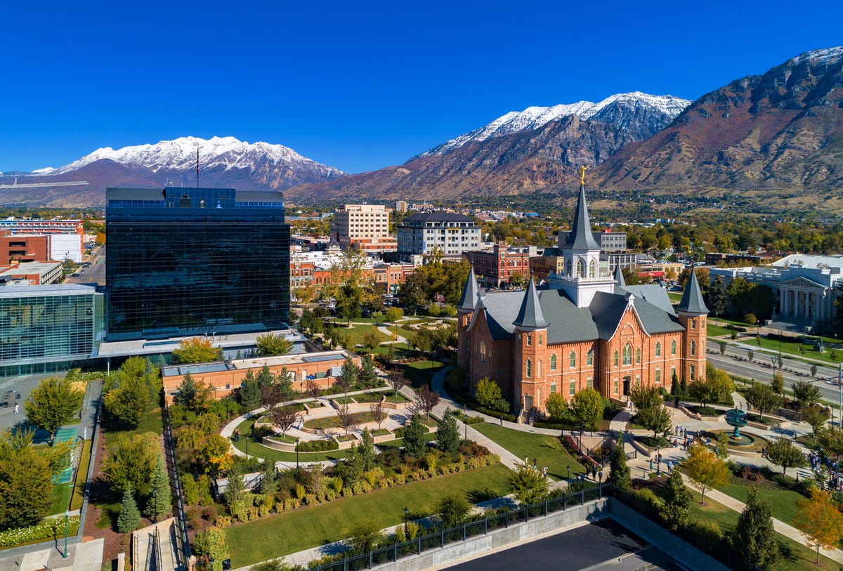 Aerial view of downtown Provo, Utah, featuring the Provo City Center Temple and the snow-capped Wasatch Mountain Range in the background.