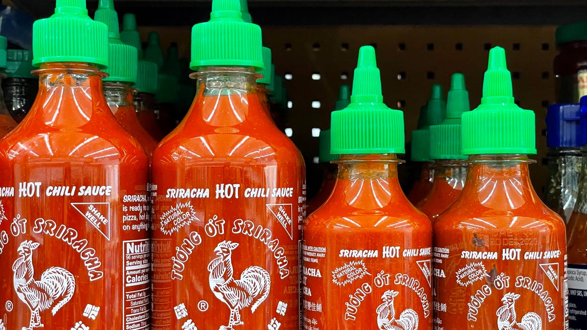 four bottles of Sriracha hot sauce sitting on a shelf