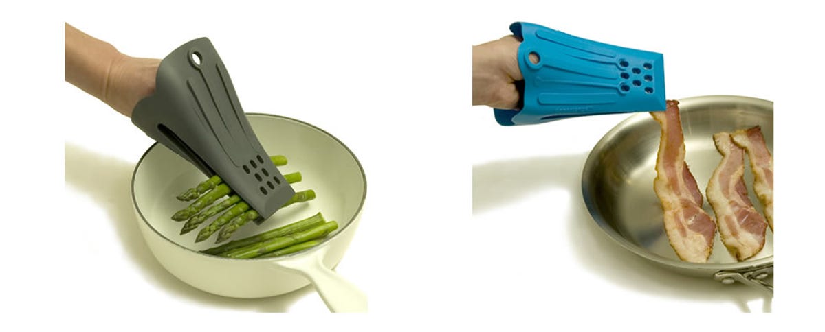 A hand covered with wearable dark green silicone tongs lifting asparagus from a pan