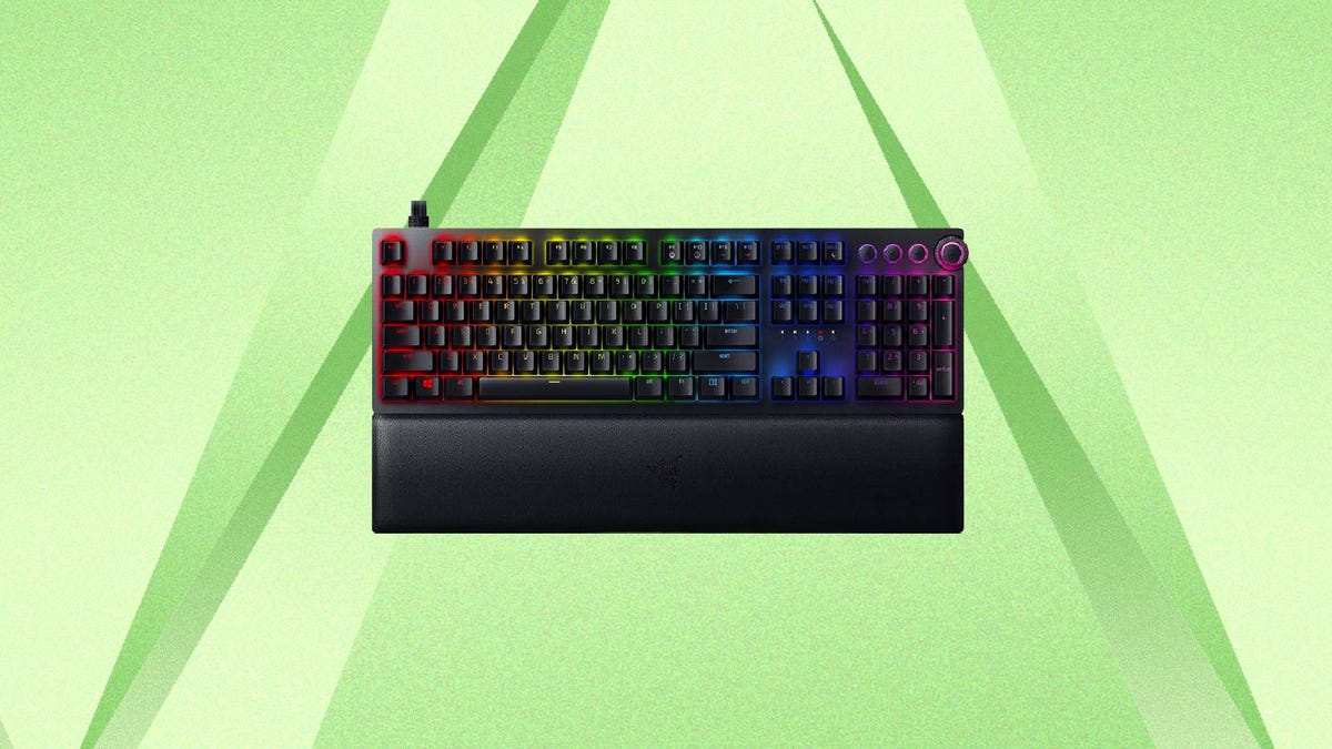 A Razer gaming keyboard with multicolored LED lighting against a green background.