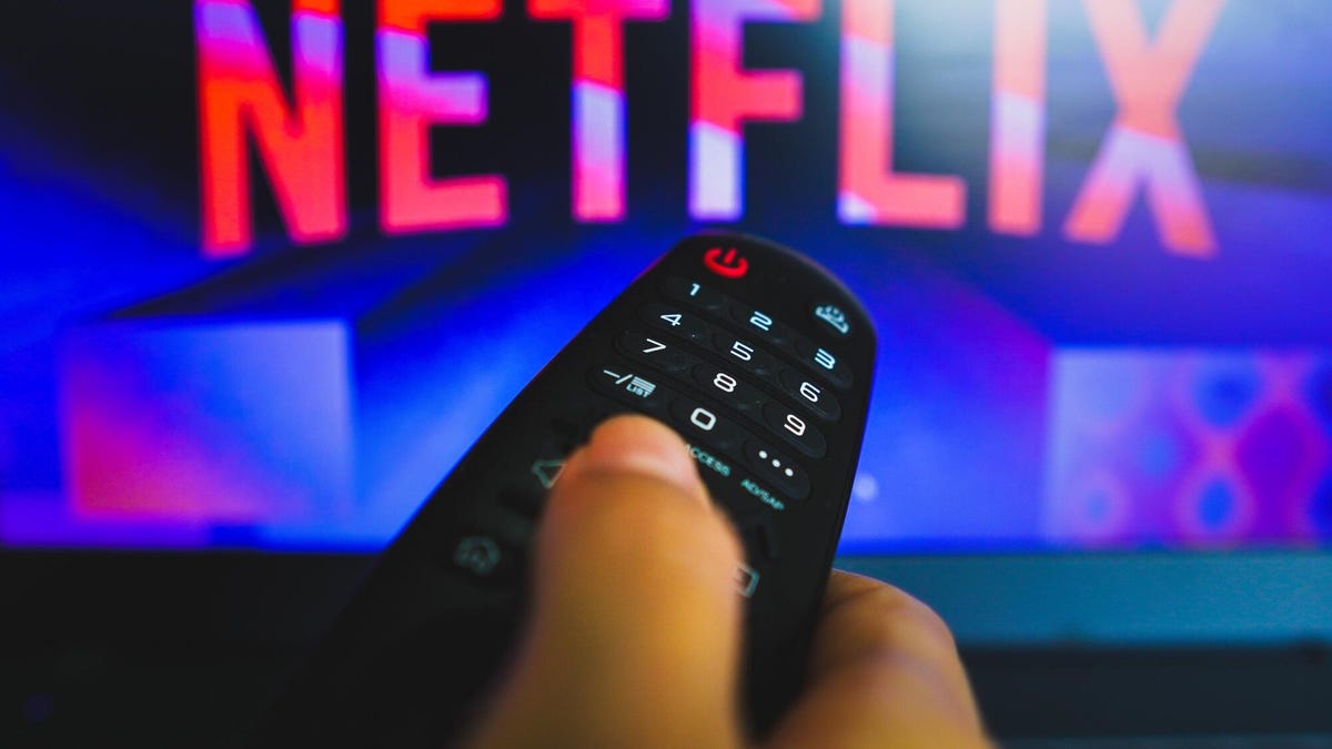 person holding remote in front of tv screen with netflix logo