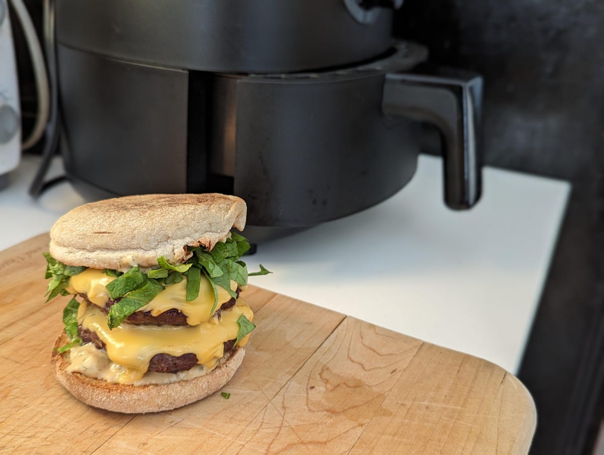 a tempting double patty cheeseburger sits next to an air fryer