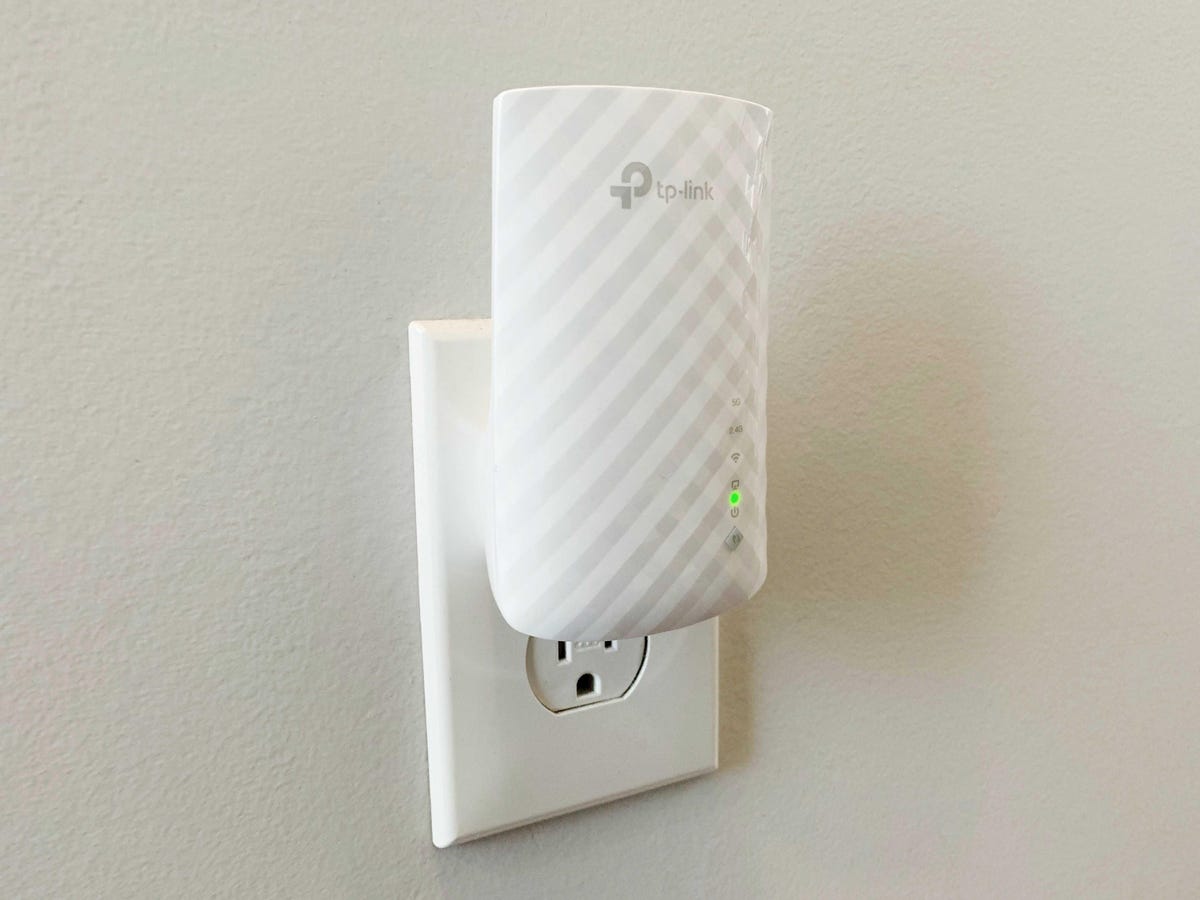 A close up of a tplink range extender plugged into an outlet