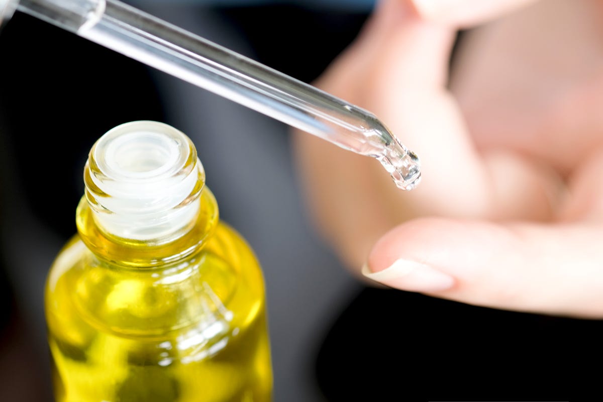 Close-up of vitamin E oil being applied to finger tip