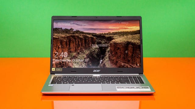 An Acer Aspire 5 laptop on an orange countertop with a green background.
