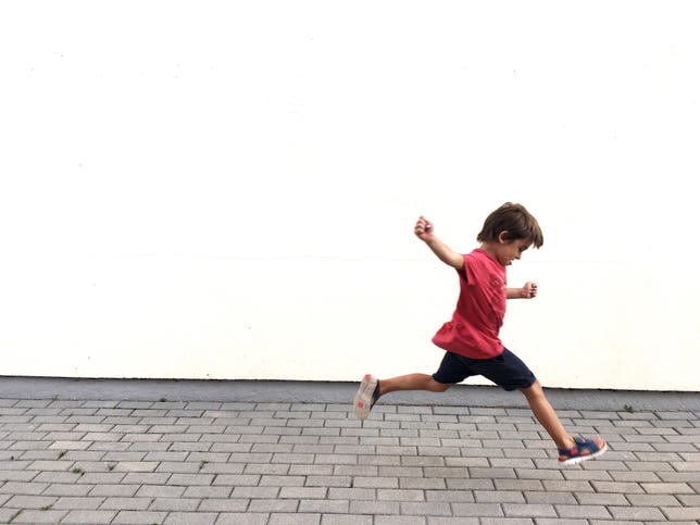 A young boy running on pavement