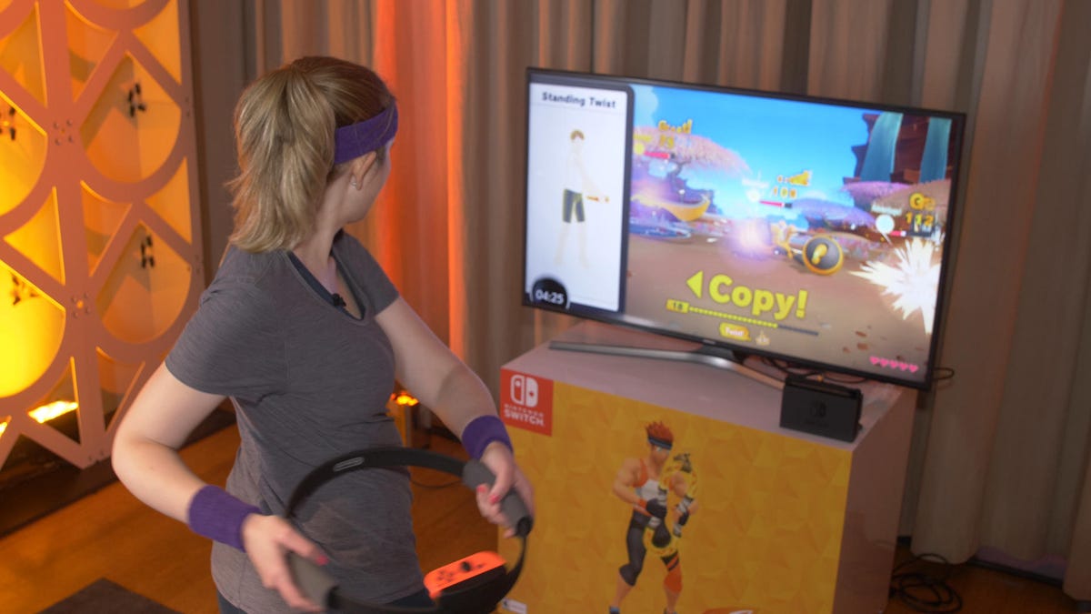 A woman works out using the Ring-Con controller in front of at TV.