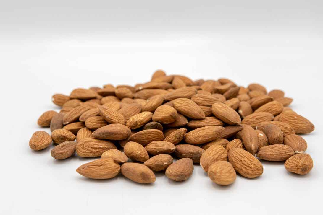 Raw almonds are spread on a white background