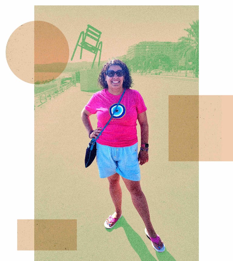 A woman in a T-shirt, shorts and sandals standing on a beachfront walk