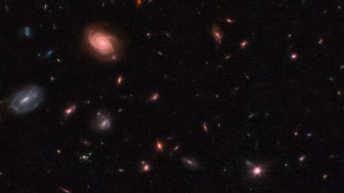spiral galaxies and distant galaxies are visible against the black void of space