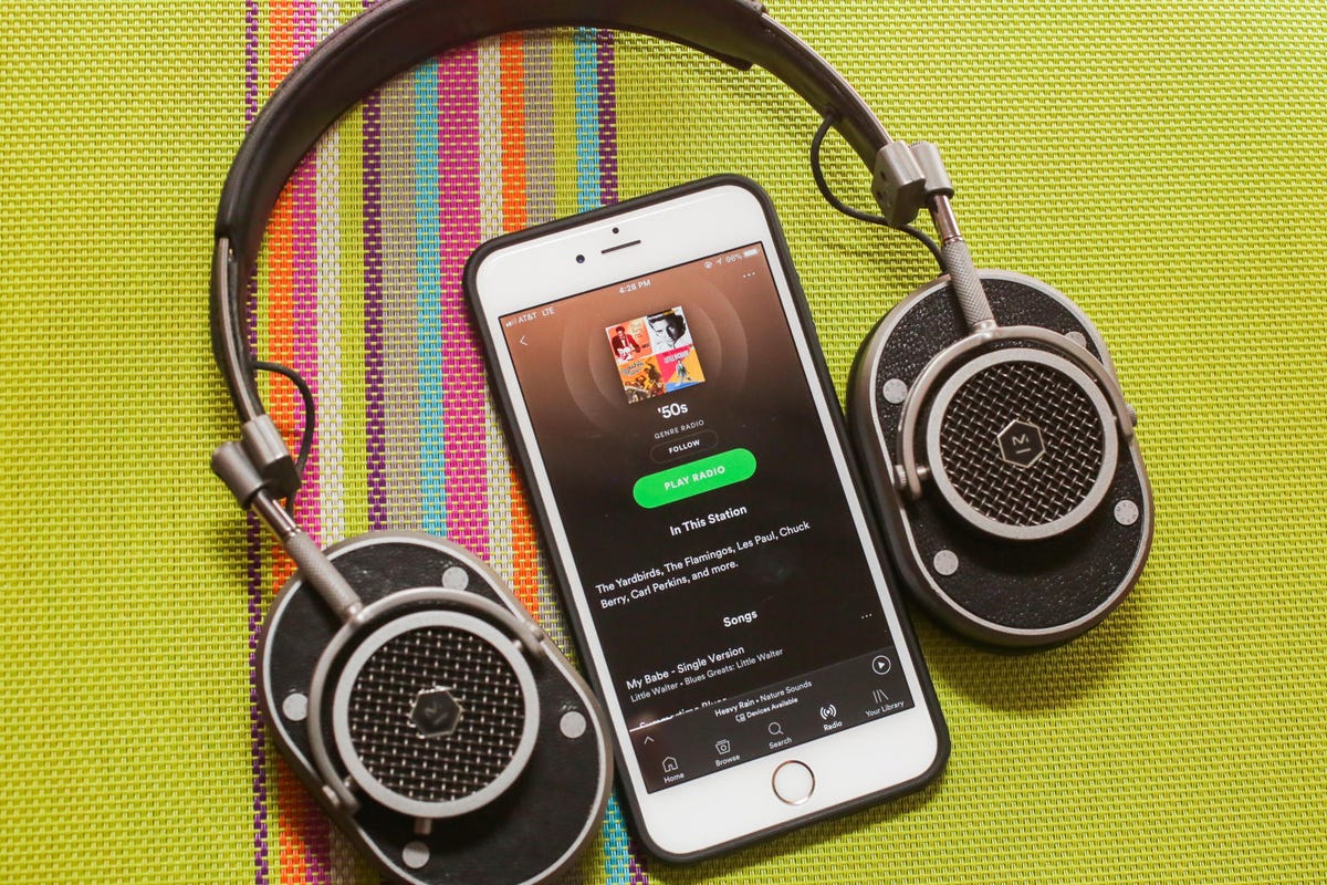 spotify app on a phone and a pair of headphones against a striped green background