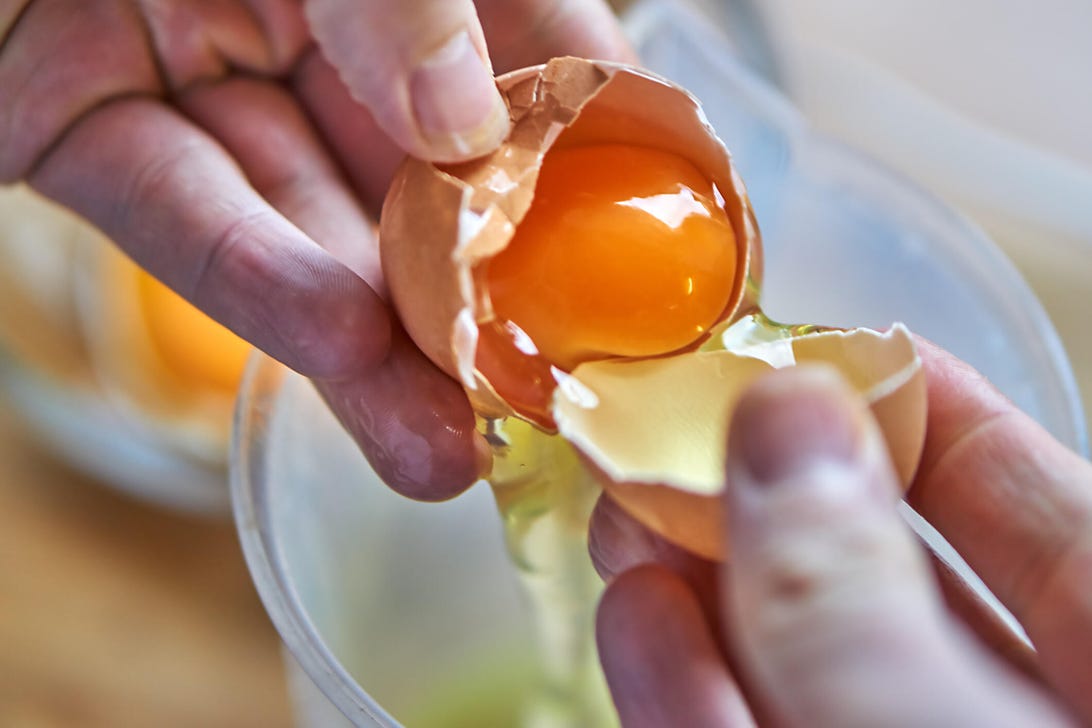 close-up of a person cracking an egg into a bowl