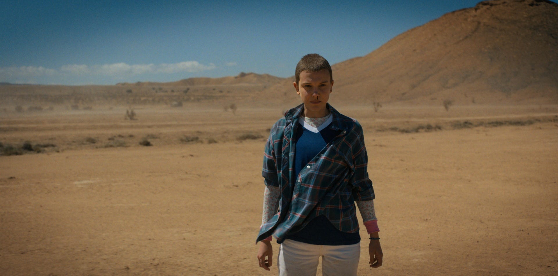 A battered but unbowed Eleven stands in the desert in Netflix series Stranger Things.
