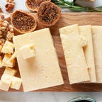 block of cheese and figs on a board