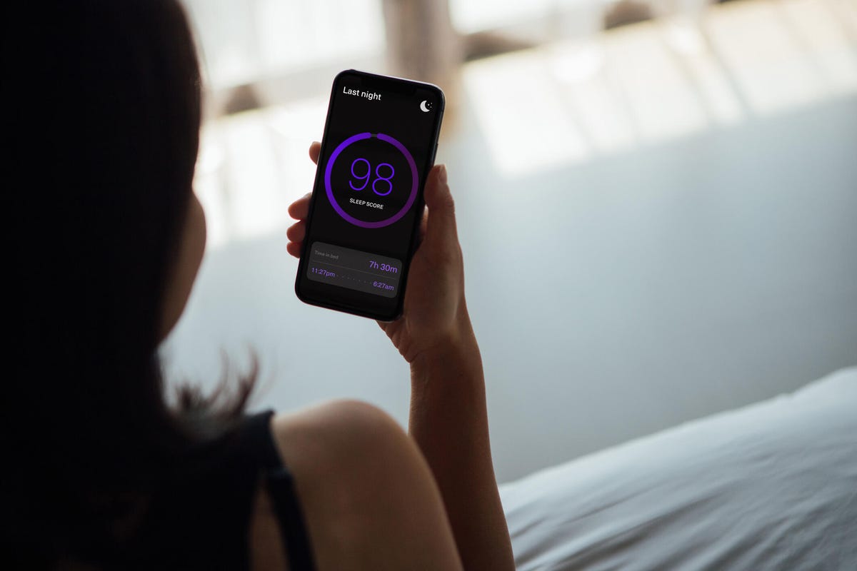 Rear view of young woman using sleep app to track her sleep score.