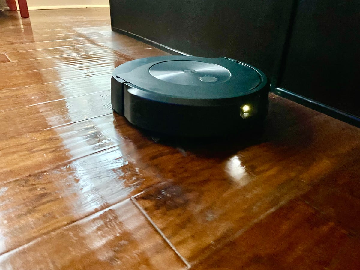 An iRobot Roomba Combo J7 Plus mops a hardwood floor. When it reaches carpeted areas, the cleaner will lift the mopping pad up over top of itself to keep them dry.