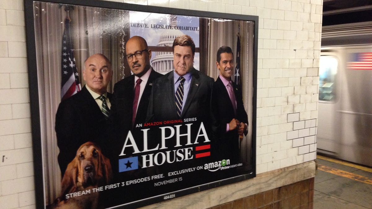 An ad poster with the four stars of "Alpha House" on a station wall as a subway speeds by