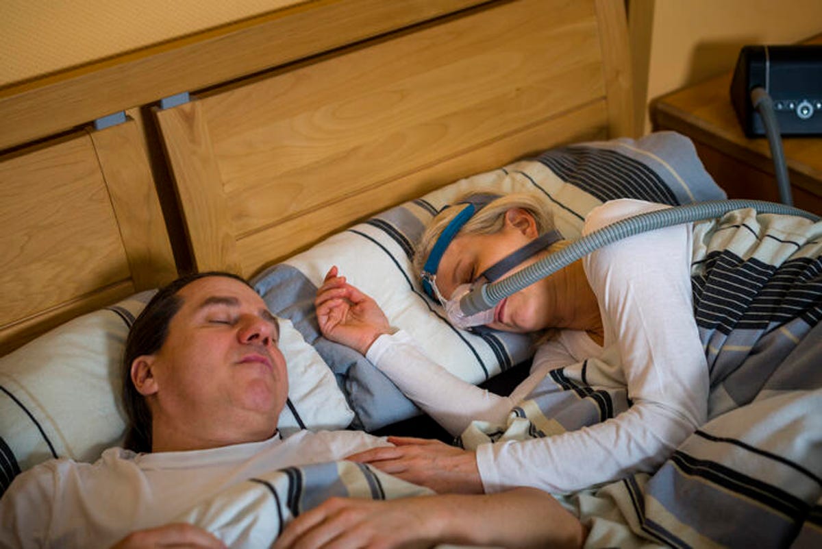 Woman sleeping next to her partner while wearing a CPAP machine