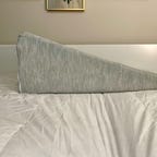 Helix Wedge pillow on a white bed.