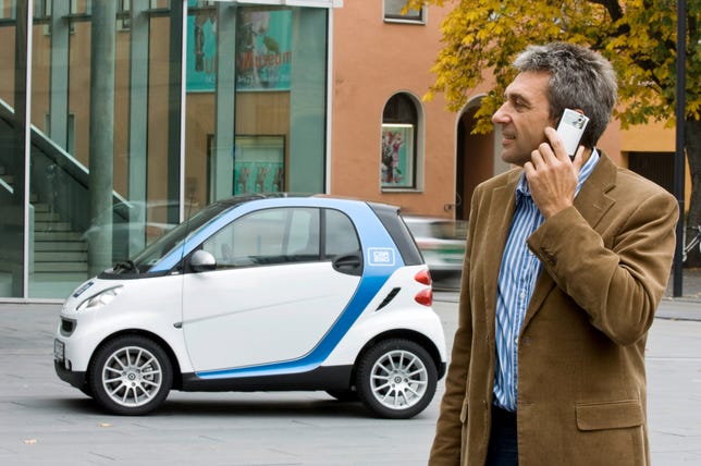 Dude on a phone near a Smart fortwo.
