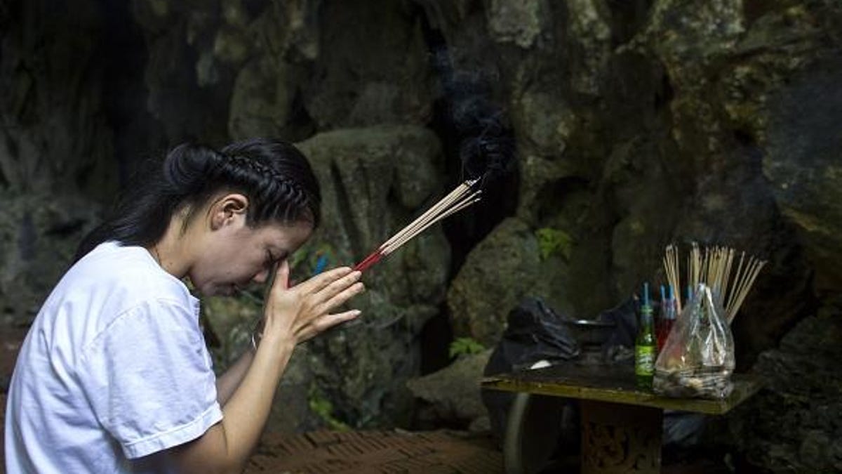 A family member prays before a shrine in the Tham Luang cave area as rescue operations continue for the 12 boys and their soccer coach trapped in a flooded cavern.
