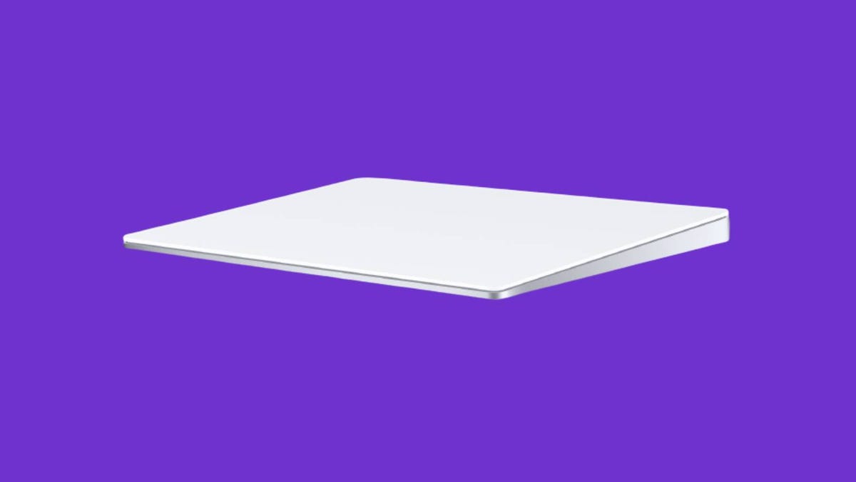 A white Apple Magic Trackpad 2 against a purple background.