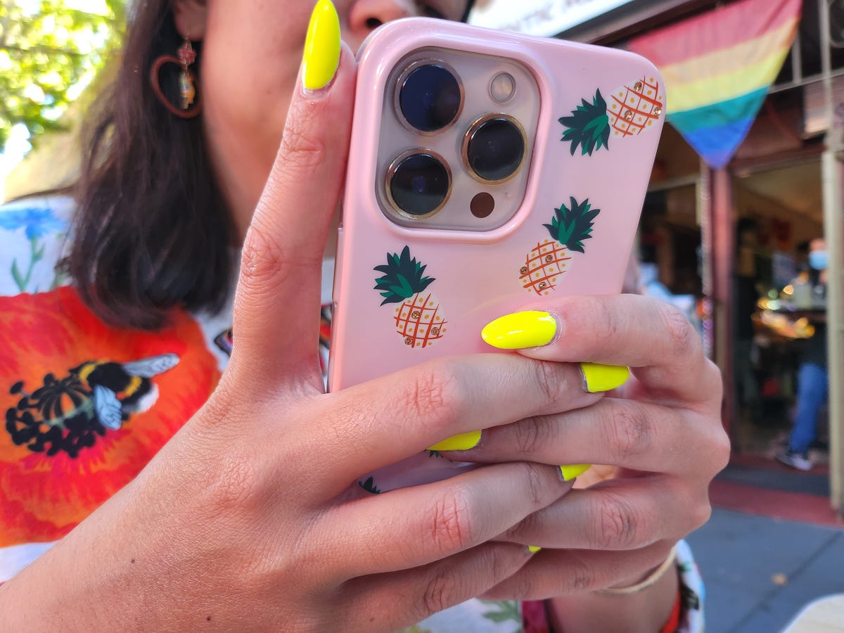 A woman with yellow fingernails holding a phone with a pink case