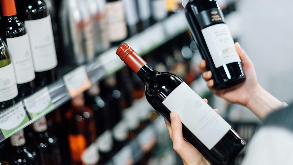 shopper comparing two bottles of red wine
