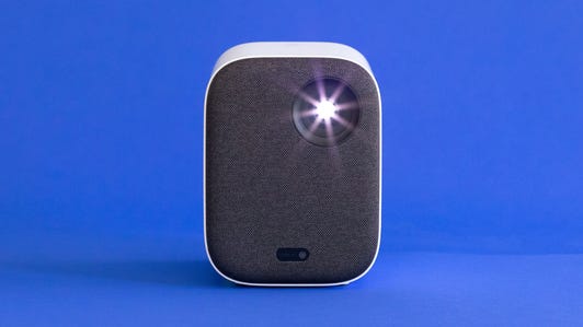 The small Xiaomi Mi Smart Projector 2 sits on a blue background.