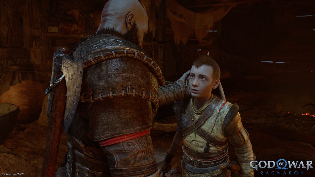 Kratos affectionately cups the head of his son, Atreus.