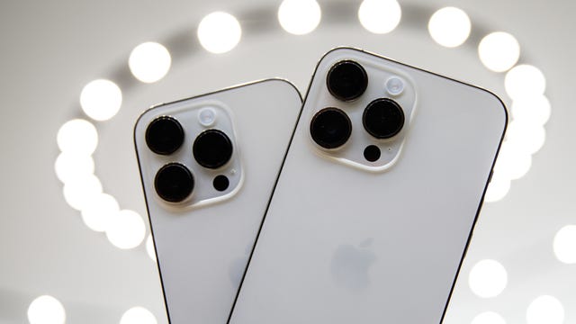 iPhone 14 Pro and iPhone 14 Pro Max seen from the rear, ringed by a halo of white lights