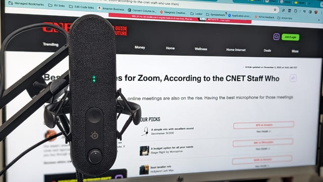 A grey microphone on a boom with Cnet open behind it