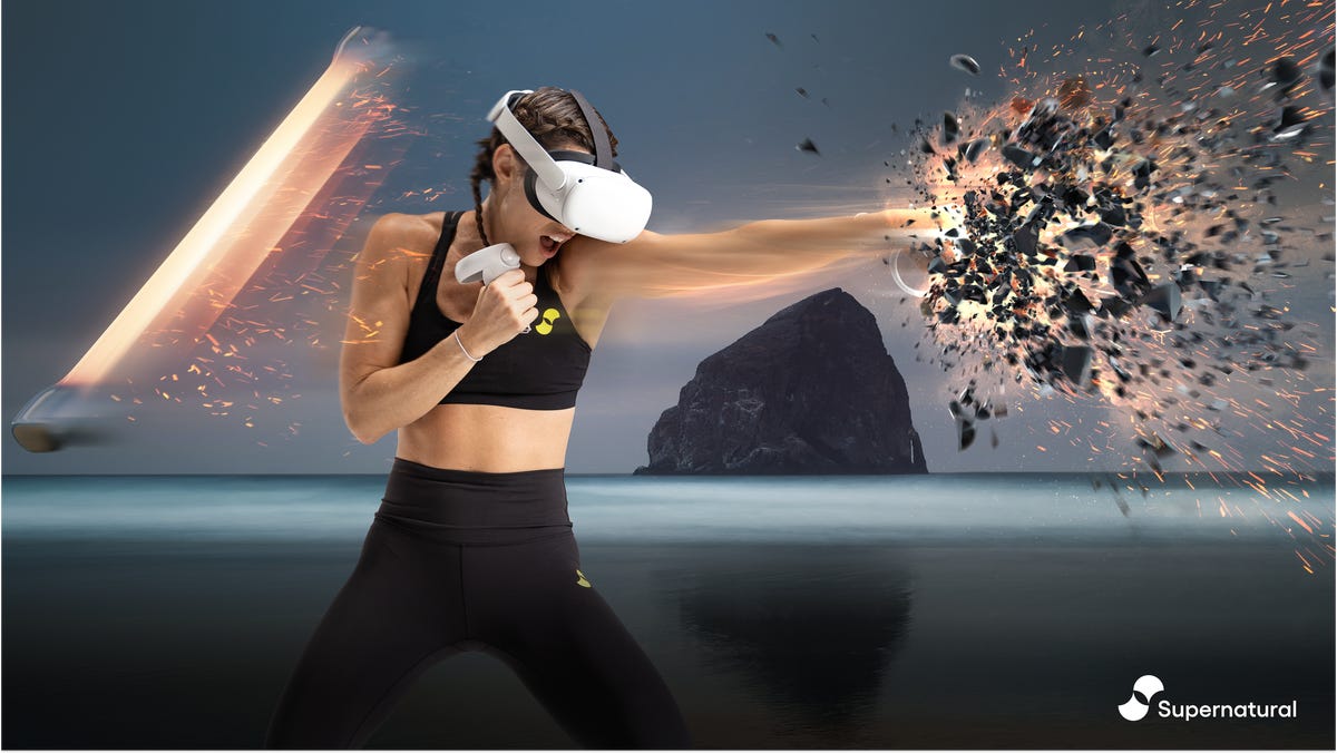 A woman wearing a VR headset punches an object, shattering it
