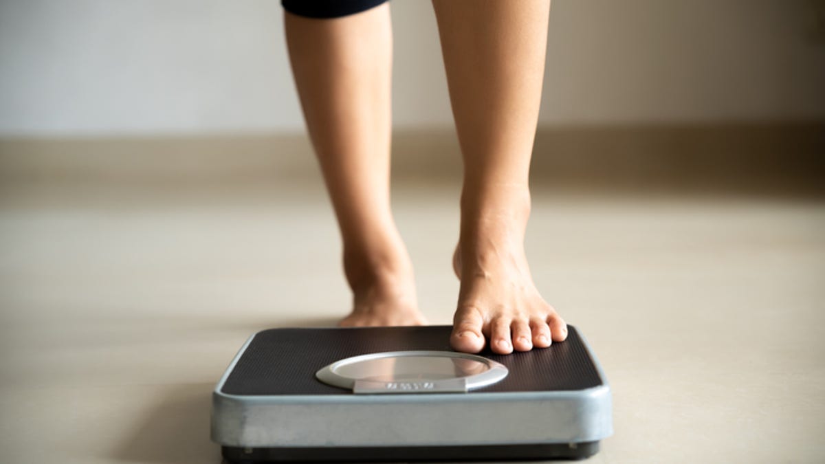 Young woman stepping onto a scale to weigh herself