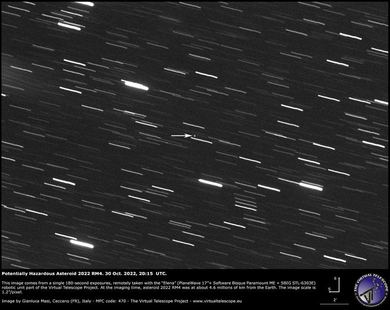 Black and white image shows streaks of moving light with an arrow pointing out a small bright dot that represents asteroid 2022 RM4.