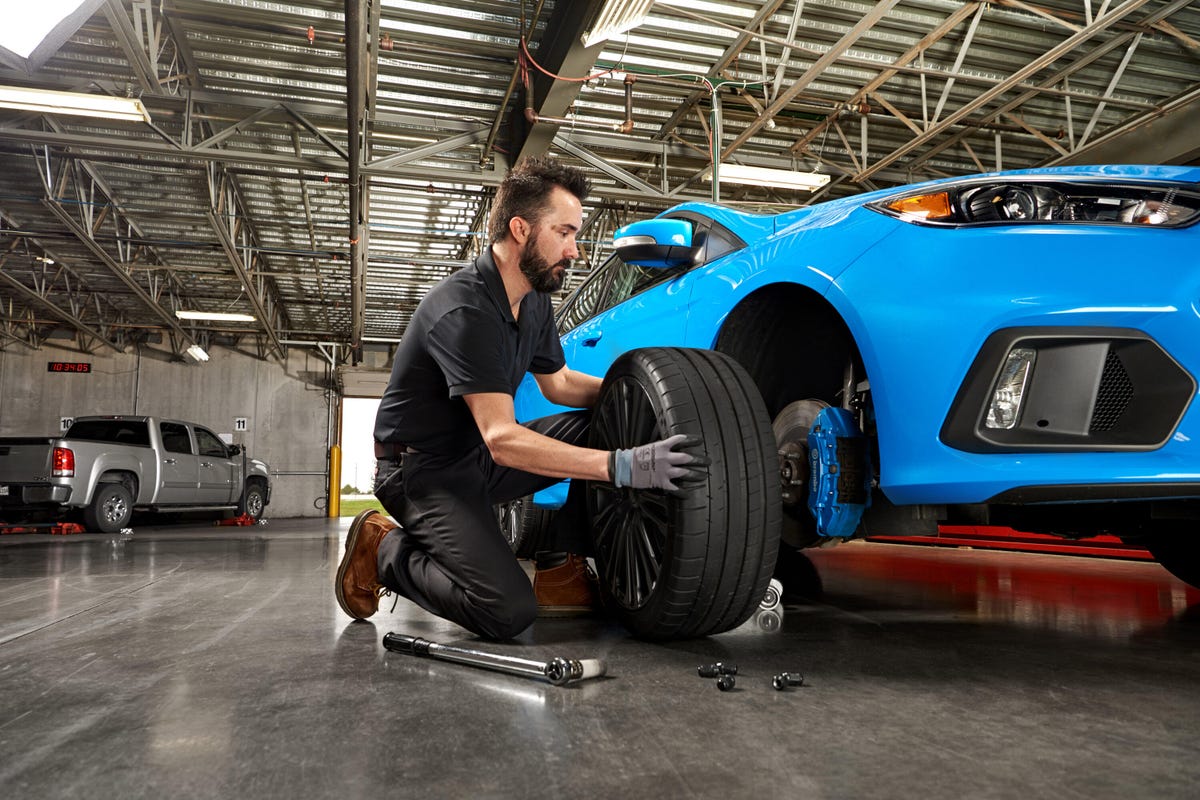 A man installs a tire on a blue car