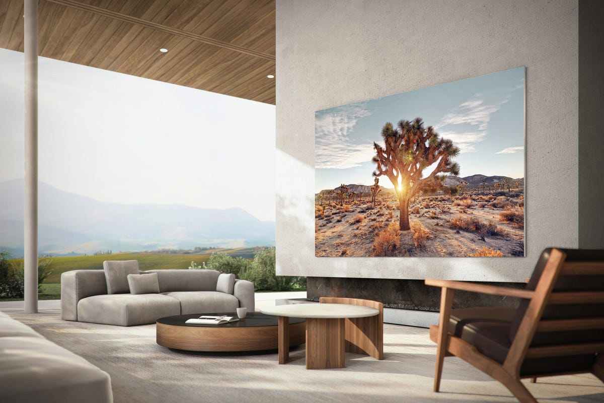 An open living room with a view of the mountains. A massive TV hangs on the wall.