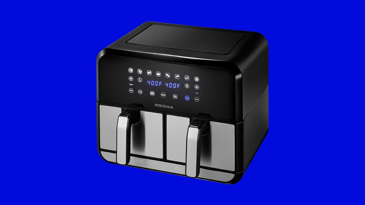 A black and silver Insignia air fryer against a blue background.