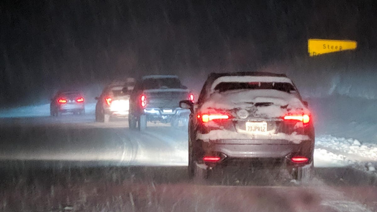Cars lined up driving through a snowstorm