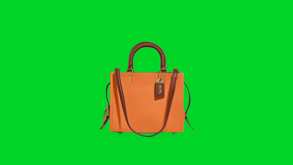A peach purse with brown leather strap on a green background