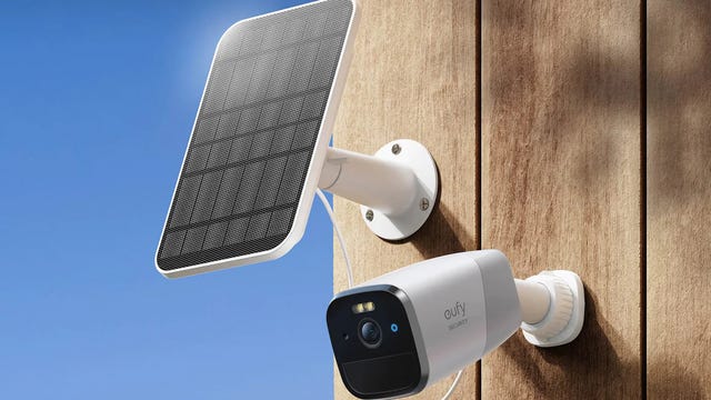 A Eufy cam mounted outside on a wood board wall with the Eufy solar panel installed above it facing the sun.