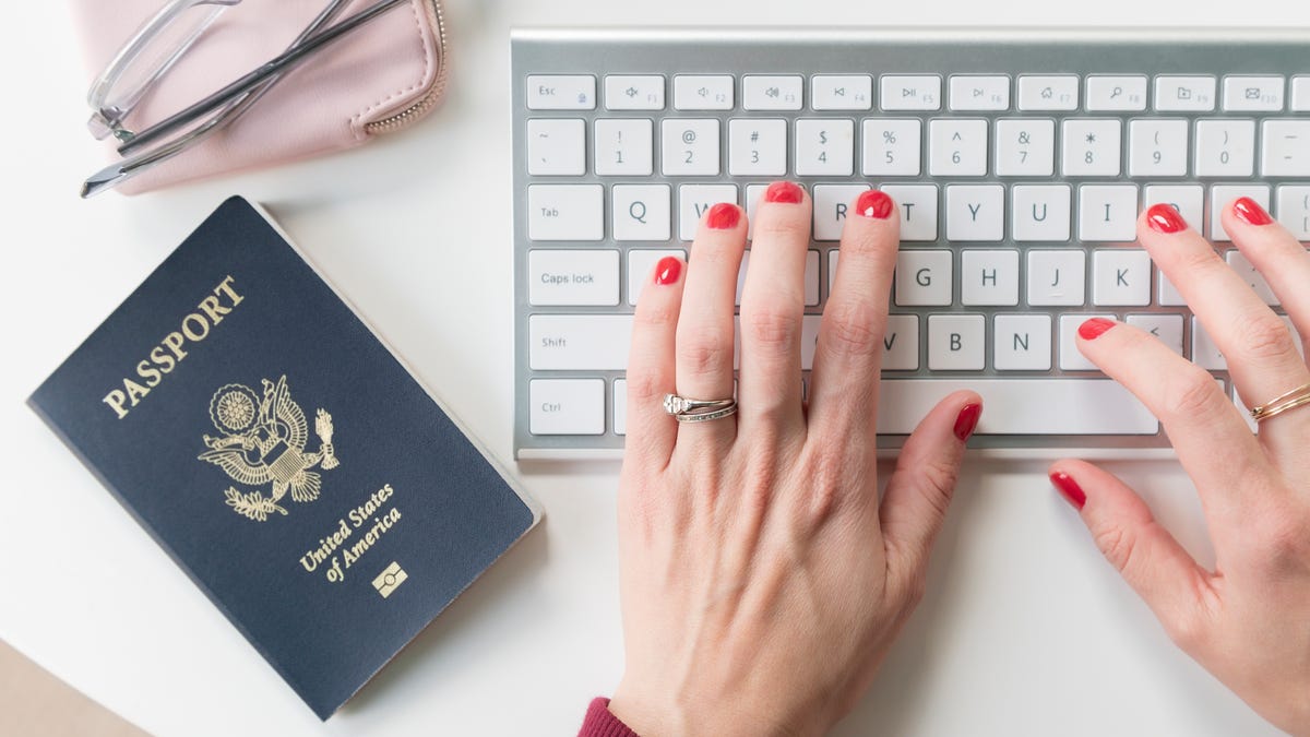 A US passport sits next to a person typing on a keyboard