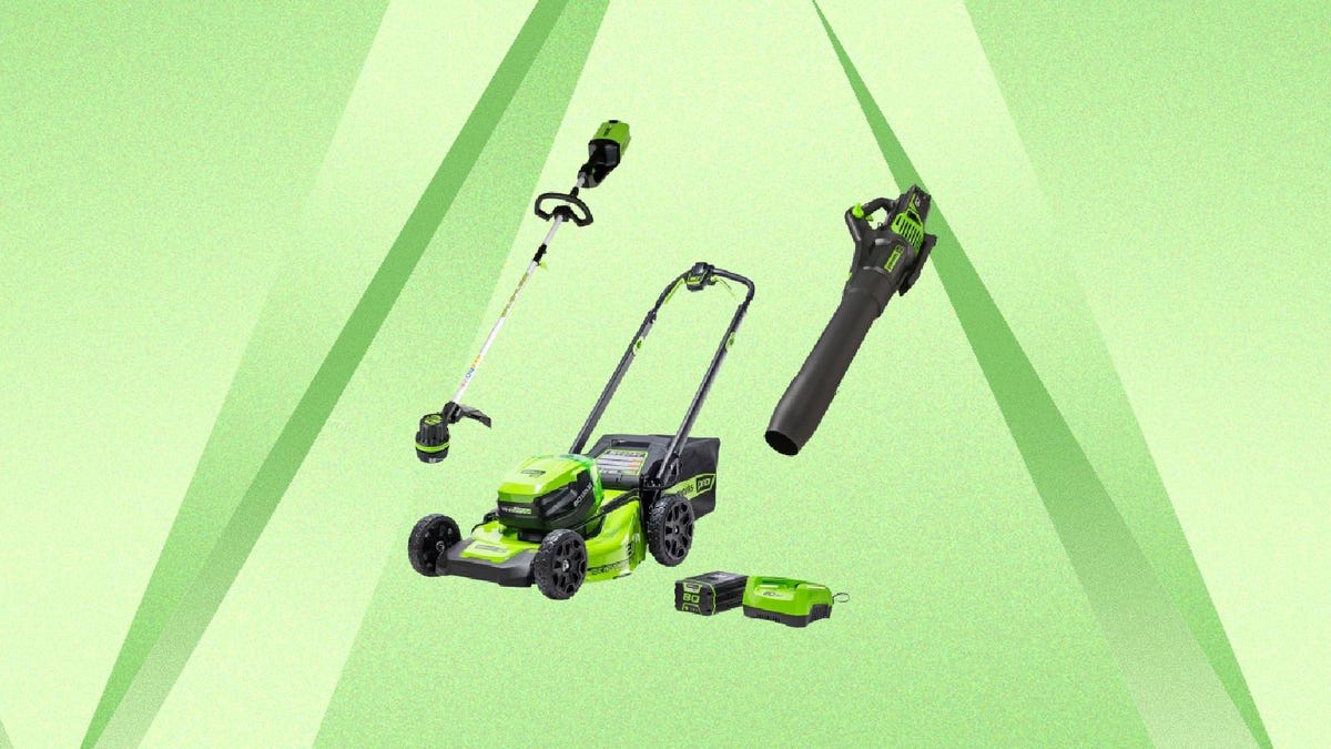 A Greenworks lawn mower, sting trimmer, leaf blower and batteries against a green background.