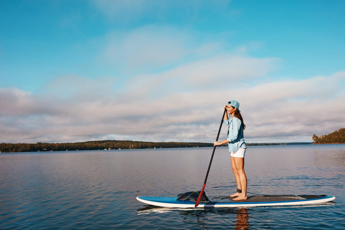 Shot of a young woman paddle boarding on a lake