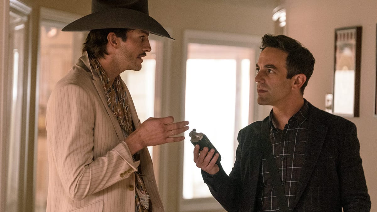 A man in a cowboy hat talking to a man holding a recording device.