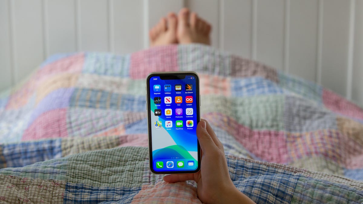 Person relaxing in bed with iPhone