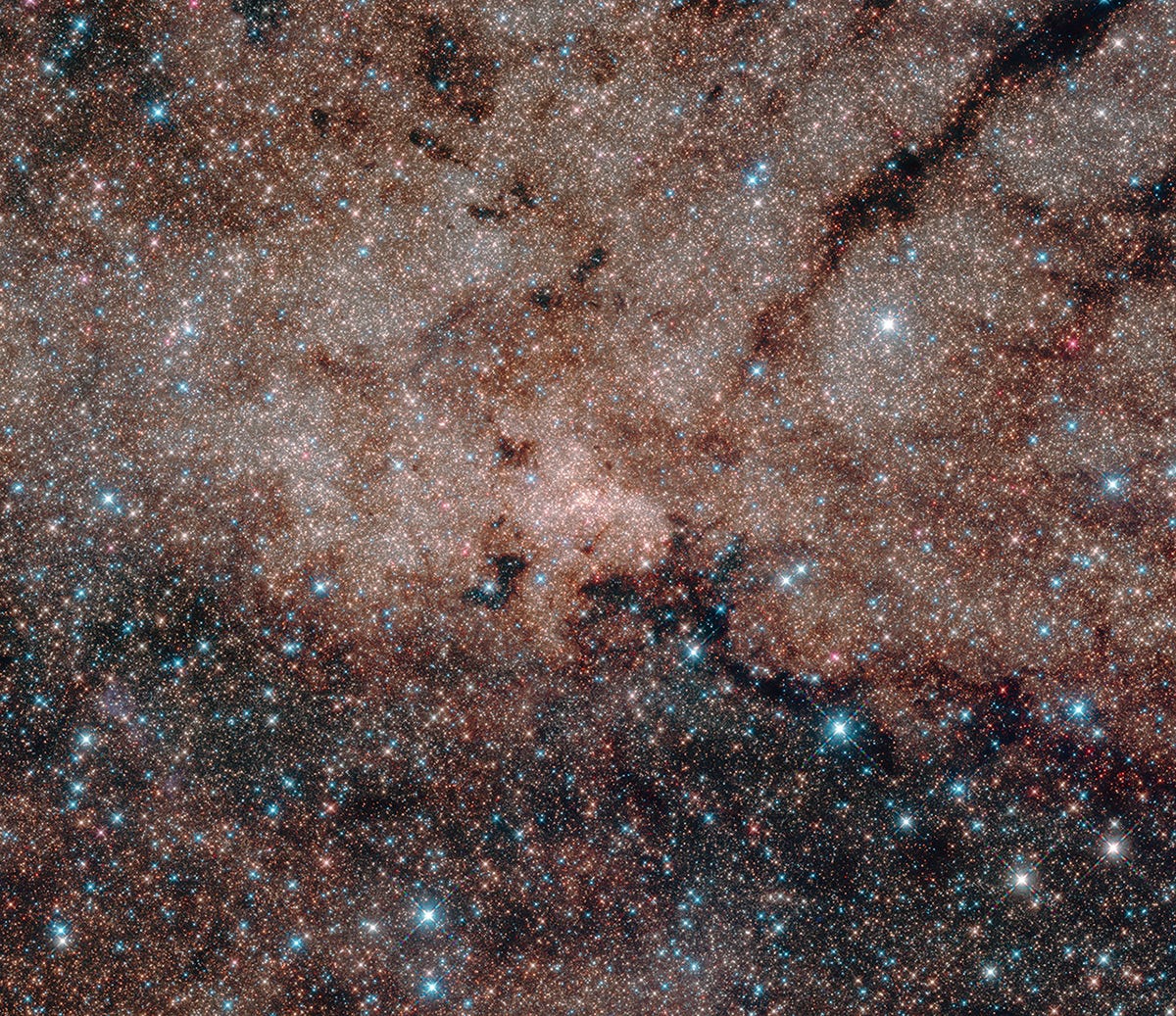 A field of stars at the centre of the Milky Way galaxy, showing a dusty red cloud and blue foreground stars