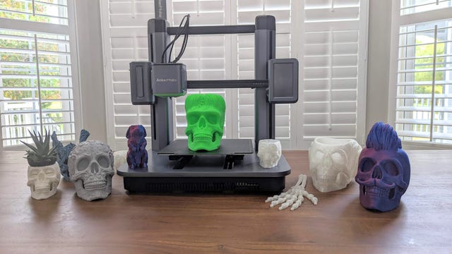 AnkerMake M5 3D printer on a table with a selection of printed skulls
