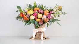 a bouquet of different colored flowers in a burlap sack with a ribbon